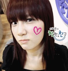 a girl with pink heart painted on her cheek and nose in front of the camera