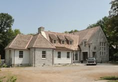 a truck is parked in front of a large stone house with two storyed windows