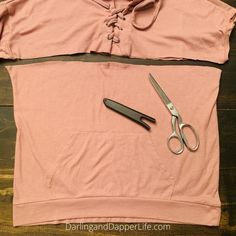 a pair of scissors sitting on top of a pink shirt next to a pair of scissors