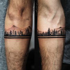 two men's legs with trees and mountains tattoo on their thighs, one is black and white