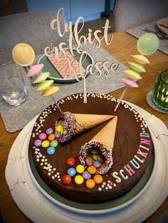 a chocolate birthday cake with an ice cream cone and candies on the top, surrounded by confetti