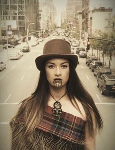 a woman with long hair wearing a brown hat and fur vest standing in the middle of a street