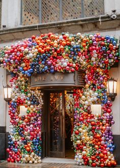 an entrance to a building decorated with christmas balls and ornaments on the outside, in front of a street light