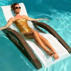 a woman in a gold bathing suit is laying on a lounge chair by the pool