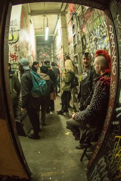 a group of people standing in an alley with graffiti on the walls