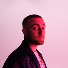 a man with a beard and piercings standing in front of a white wall