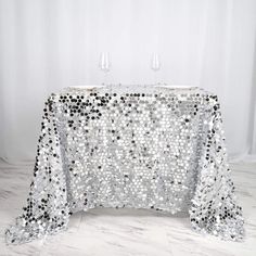 a table covered in silver sequins with two wine glasses on top of it