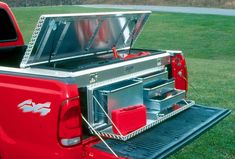 the back end of a red pickup truck with an open tool box on it's bed