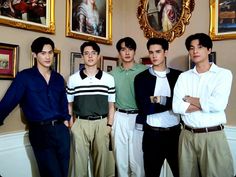 four young men are posing for a photo in front of some pictures on the wall