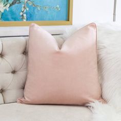 a pink pillow sitting on top of a couch next to a white fur covered chair