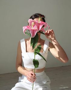 a woman sitting on the floor with a flower in her mouth