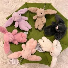 several small stuffed animals are sitting on a green cloth covered tray with tags attached to them