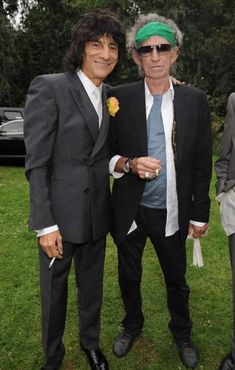 two men standing next to each other wearing suits and ties with green headbands