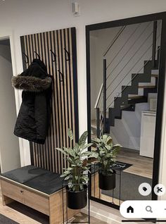 an entry way with a coat rack and potted plant in front of the mirror