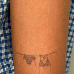 a person with a tattoo on their arm that has clothes hanging out to dry them