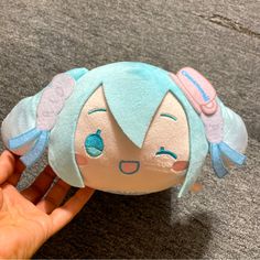 a hand is holding a small stuffed animal with blue hair and wings on it's head