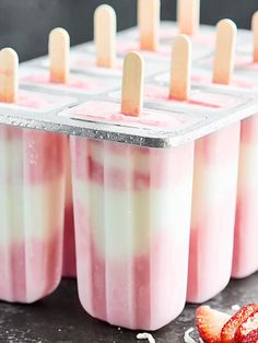 three popsicles with strawberries in them on a table next to other popsicles