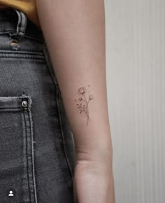 a woman's arm with a small flower tattoo on the left side of her right arm