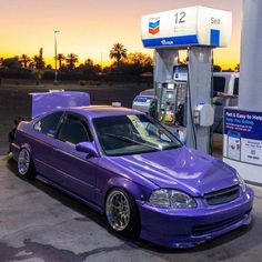 a purple car is parked in front of a gas pump