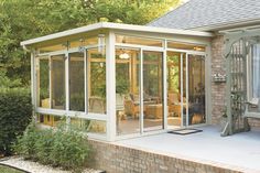 an enclosed patio with glass walls and brick steps leading up to the back of the house