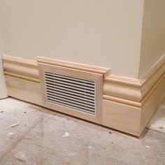 the corner of a room with a vent on it's side and wood trim