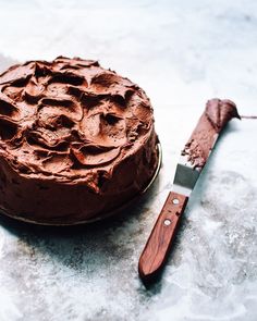 a chocolate cake sitting on top of a table next to a knife