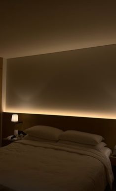 a bed with white sheets and pillows in a dimly lit room