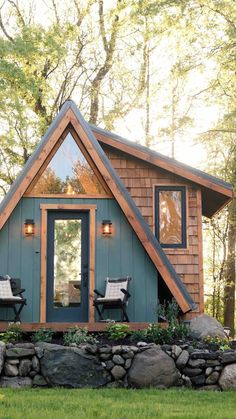 a small cabin with two chairs in front of it and a stone wall around the outside