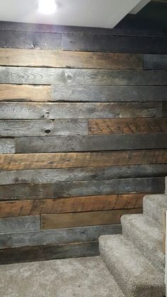 a wall made out of wooden planks in a room with carpeted stairs leading up to it