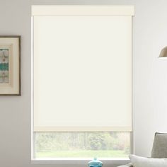 a living room with a couch, chair and window covered in white roller shades on the windowsill