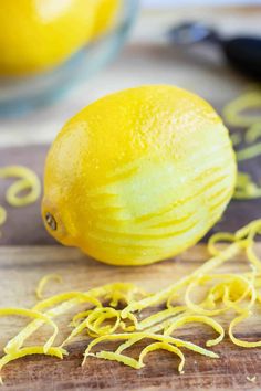 a lemon sitting on top of a wooden cutting board next to some yellow spirals