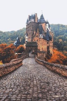 an old castle is shown in the middle of a cobblestone road that leads to it's entrance