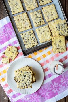 a table topped with lots of cookies next to a white plate filled with cake batter