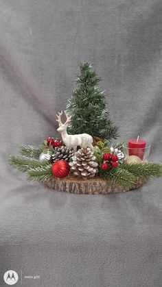 a small christmas tree with pine cones and red balls on it, surrounded by other decorations