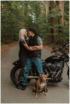 a man and woman standing next to a motorcycle with a dog sitting on the front