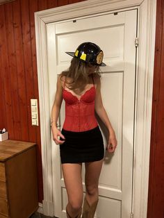 a woman in a red corset and cowboy hat standing next to a door