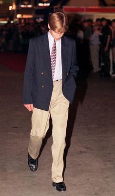 a young man in a suit and tie walking down the street with his hands in his pockets