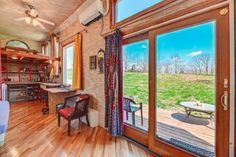 the inside of a home with wood floors and large sliding glass doors that lead out to an open field