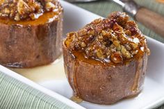 two baked desserts on a white plate with spoon and fork in the back ground