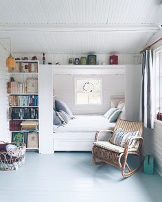 a bedroom with a bed, chair and bookshelf in the middle of it