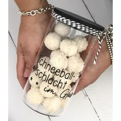 a person holding a clear container filled with white pom - poms and the words schneeball schlucht in german on it