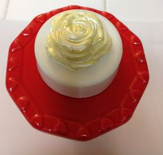 a red plate topped with a white cake covered in frosting