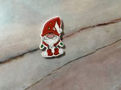 a red and white santa clause pin sitting on top of a stone floor