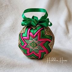 an ornament shaped like a flower with a green ribbon