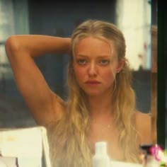 a woman sitting at a table in front of a mirror with her hair blowing back