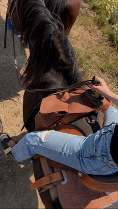 a woman riding on the back of a brown horse next to a man in jeans