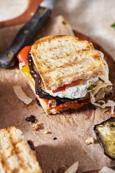 a grilled cheese sandwich sitting on top of a cutting board next to a knife