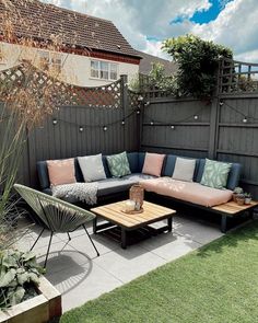 a couch and table in the middle of a small backyard area with grass on the ground