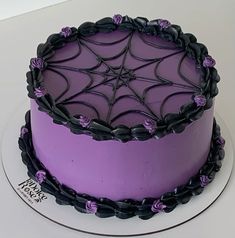 a purple cake decorated with black icing and spider webs on it's side