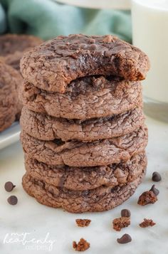 a stack of chocolate cookies next to a glass of milk